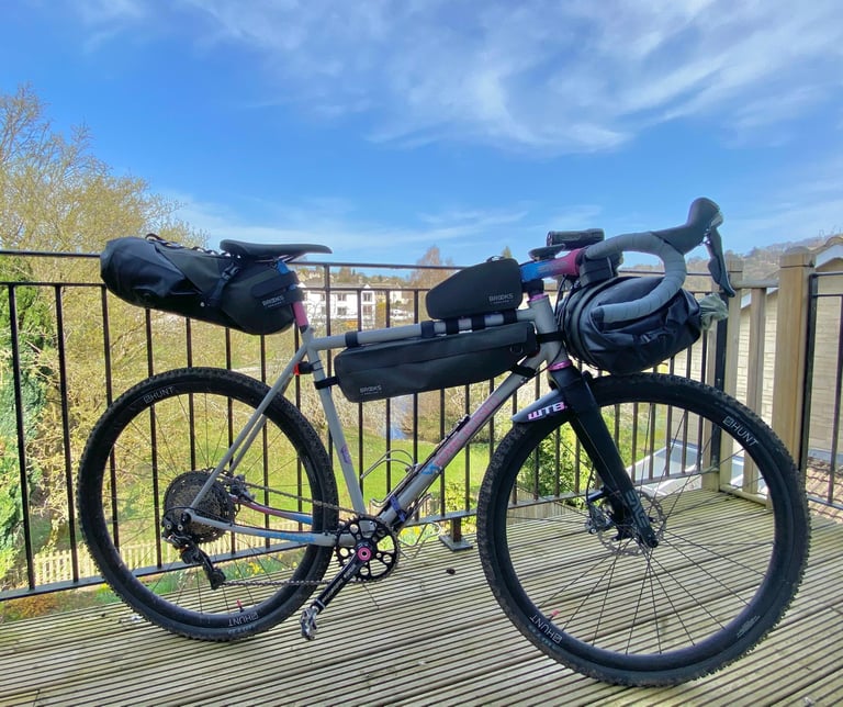 Gravel bike loaded with the Brooks Scape seat bag, top tube bag, frame bag and handlebar roll, parked on a balcony.