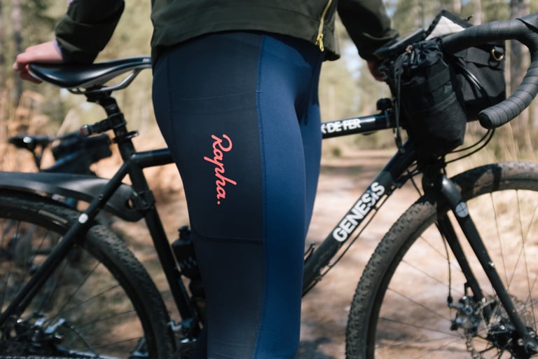 Rapha All Day Leggings thigh pocket and logo, with a black Genesis gravel bike and handlebar bag behind.