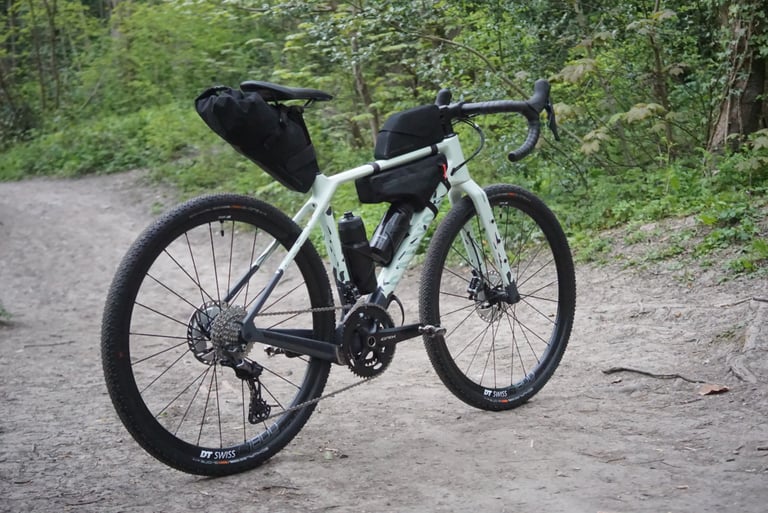 Canyon Grizl with Apidura saddle pack, frame pack and top tube bag fitted, on a woodland track.