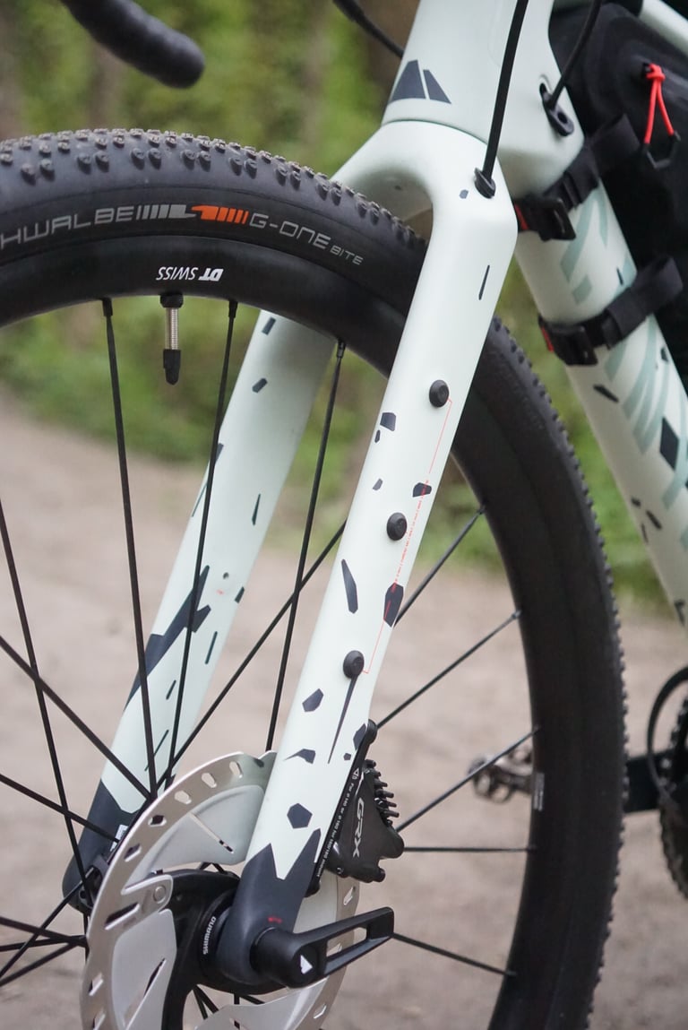 Canyon Grizl carbon fork leg with three cargo cage mounts, printed mount markings and a Shimano GRX caliper.