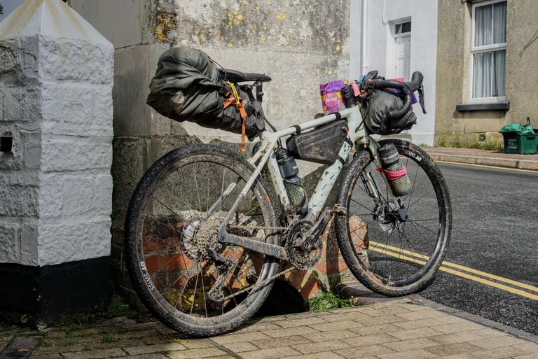 Size XS Canyon Grizl loaded with saddle pack, frame pack and handlebar bag, leant against a wall on a Devon street.