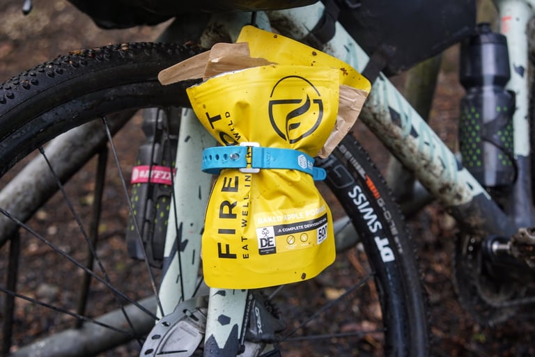 Firepot dehydrated meal pouch strapped to a Tailfin cargo cage on the Canyon Grizl's muddy fork leg.
