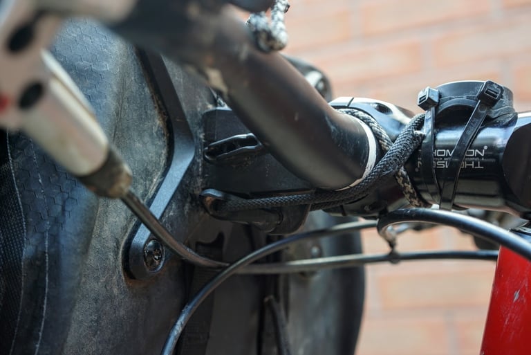 Close-up of the Ortlieb Handlebar Pack QR mounting plate, with cord wrapped around the stem and bar.