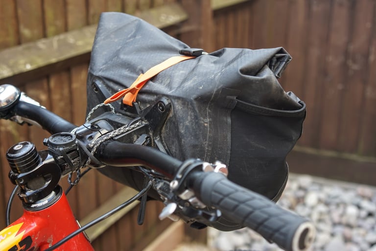 Ortlieb Handlebar Pack QR on a red flat-bar bike, with the cord mount at the stem and an orange strap over the top.
