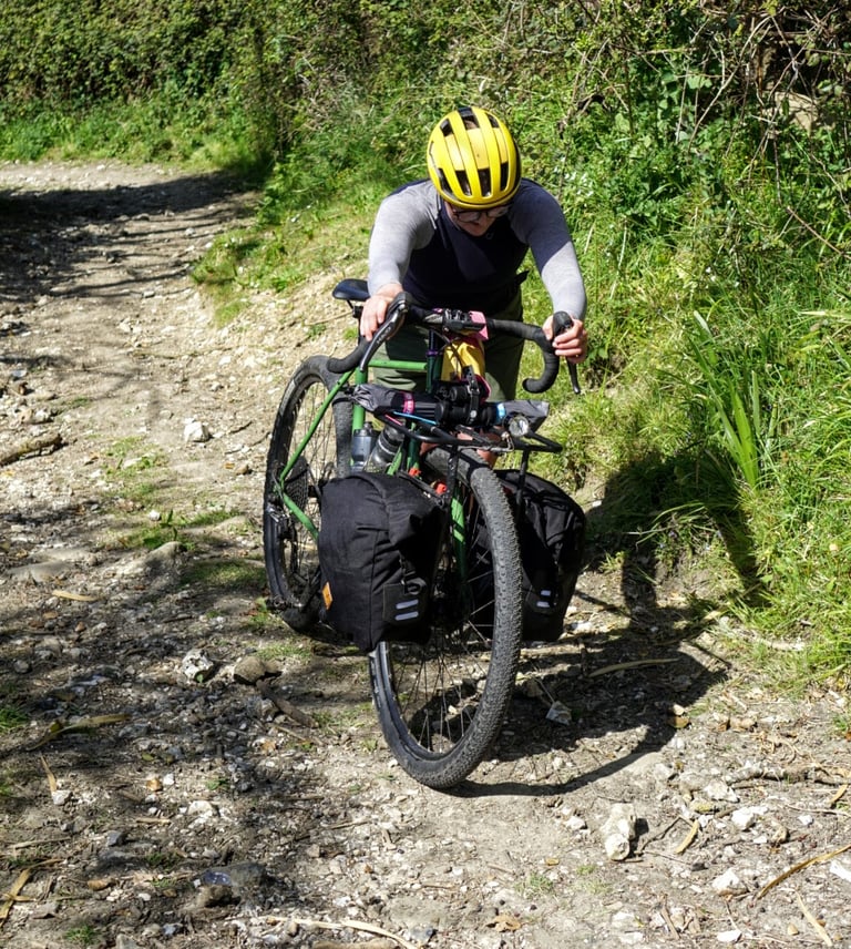 Rider pushes a loaded Fairlight Faran with front panniers up a steep, stony track in Devon.