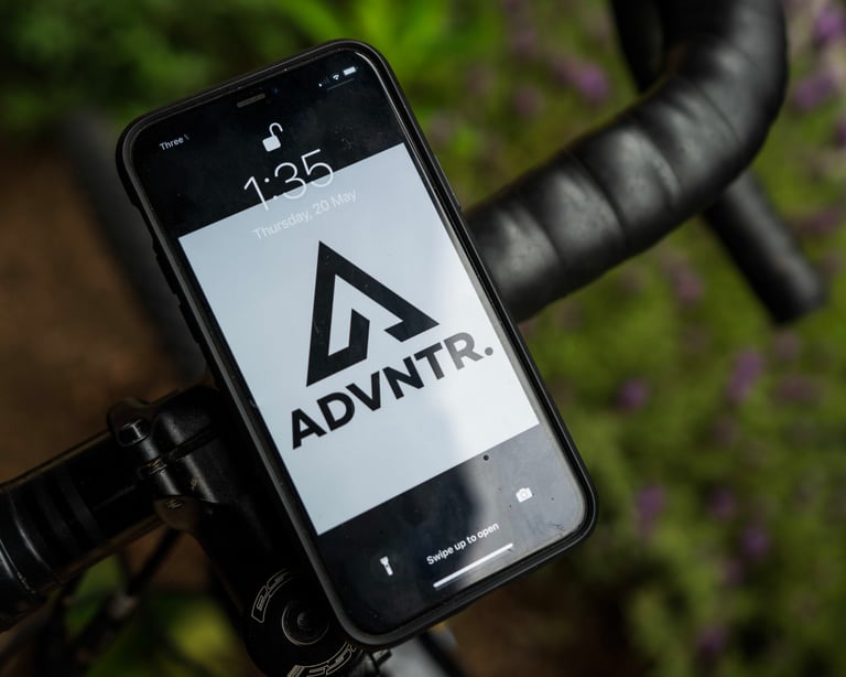 Phone locked onto drop handlebars by the Fidlock VACUUM mount, screen lit, beside the stem of a gravel bike.
