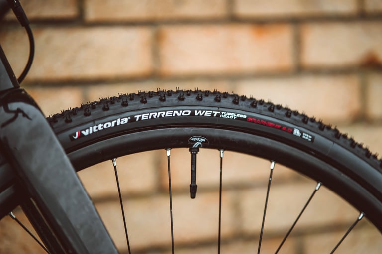 Vittoria Terreno Wet tubeless gravel tyre and valve on a black rim, set up with the Air-Liner Gravel insert.