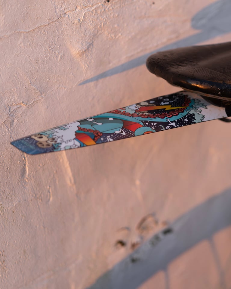 Side view of the RideGuard Gaiter rear guard in Kraken artwork, lit by low evening sun beneath a black saddle.