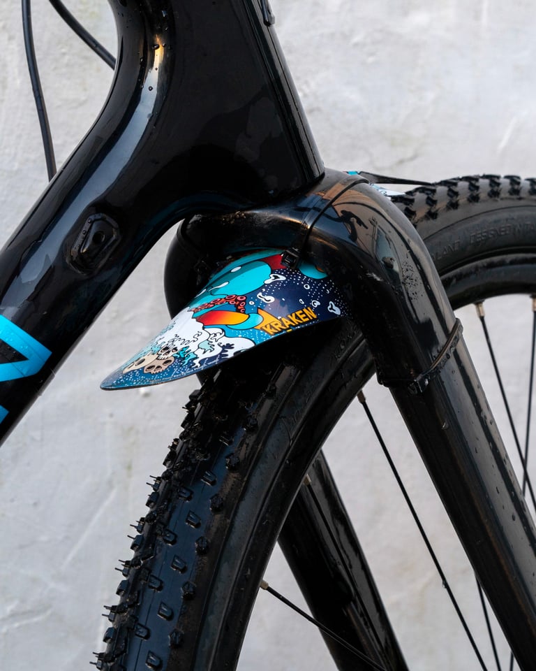 RideGuard Vision front mudguard in Kraken artwork, held to a fork leg with zip ties above a knobbly gravel tyre.
