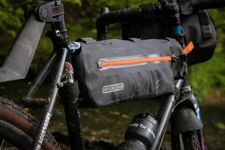 Ortlieb Frame-Pack Toptube in black with orange zip, mounted above a bottle cage and still clean after months of use.