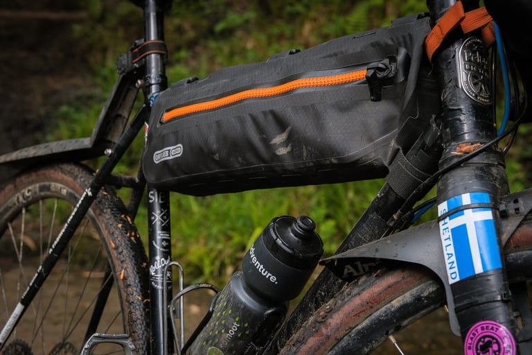 Orange waterproof zip on the Ortlieb Frame-Pack Toptube, mounted in the main triangle of a muddy bike.