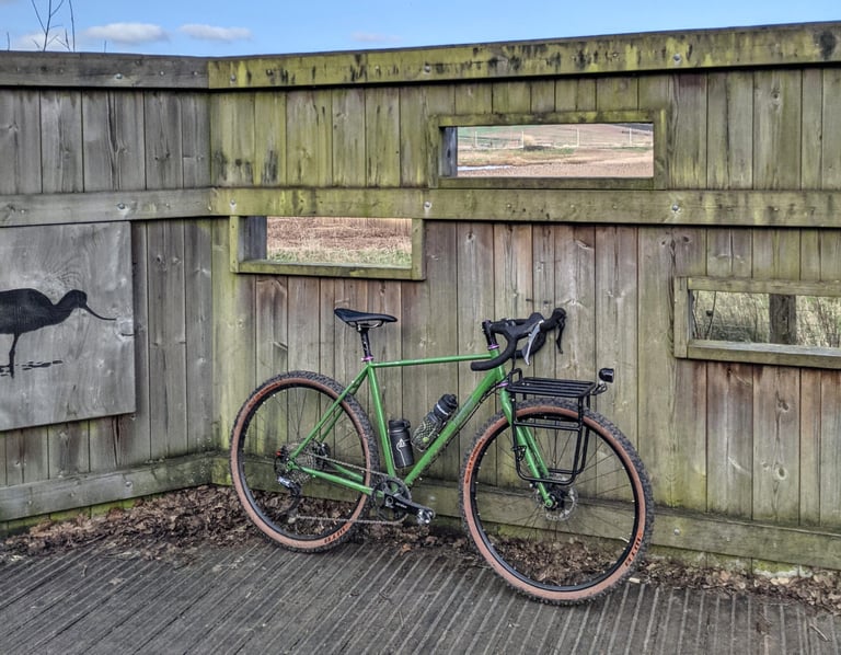 Fairlight Faran with a Specialized Pizza Rack and bottles leaning against a wooden bird hide wall.