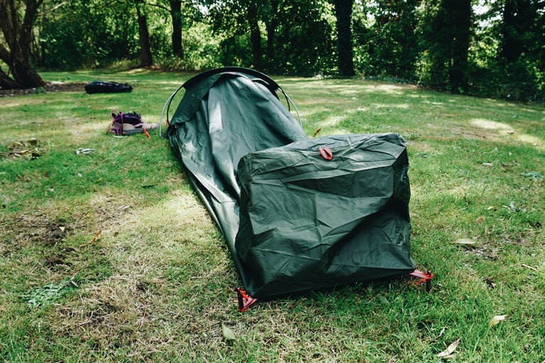 Alpkit Elan hooped bivvy pitched under trees, seen from the foot end with the two hoops at the head end beyond.