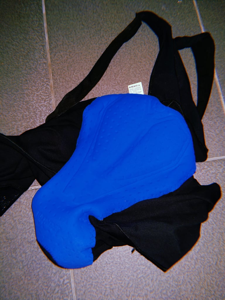 Santini Gravel Bib turned inside out on a tiled floor, showing the blue C3 chamois pad and black straps.
