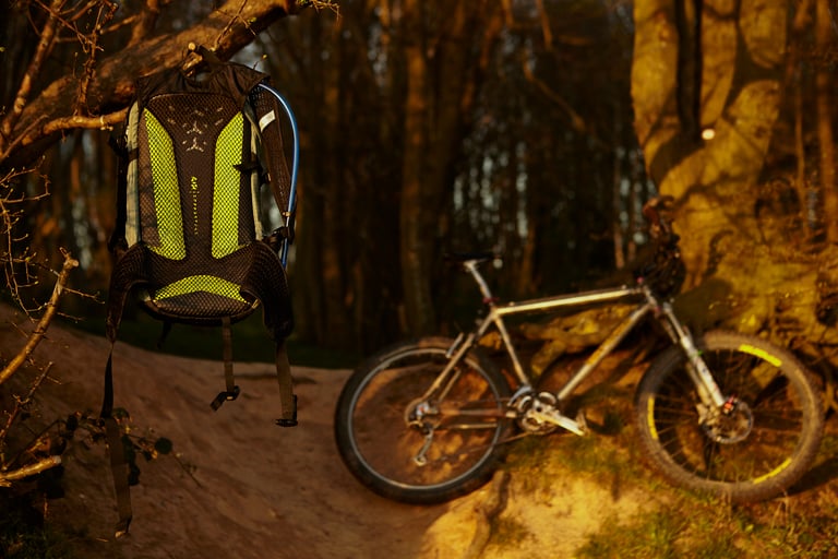 Camelbak Mule Pro 14L hydration pack hanging from a branch, with a mountain bike leaning on a tree behind.