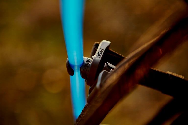 Blue Camelbak Mule Pro hose held by a small magnetic guide clip on the shoulder strap.