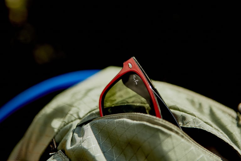 Red-framed sunglasses tucked into the soft-lined top pocket of the Camelbak Mule Pro.