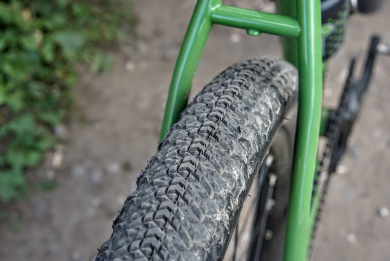 Close-up of the Teravail Sparwood tread, with chevron-shaped centre lugs, on a green-framed bike over a gravel path.