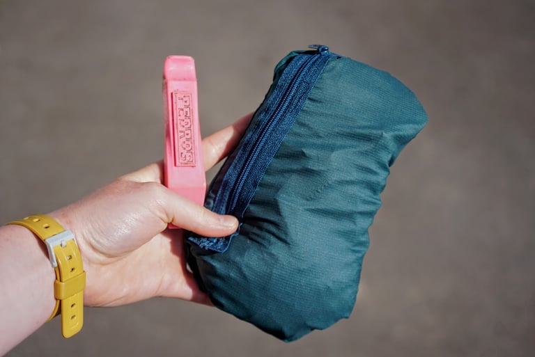 Velocio Ultralight Jacket packed into its zipped pocket, held beside a pink Pedro's tyre lever for scale.