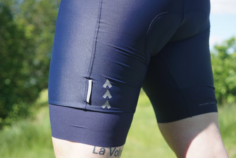 Reflective strip and three printed chevrons above the leg gripper of navy Triban RC500 bib shorts.