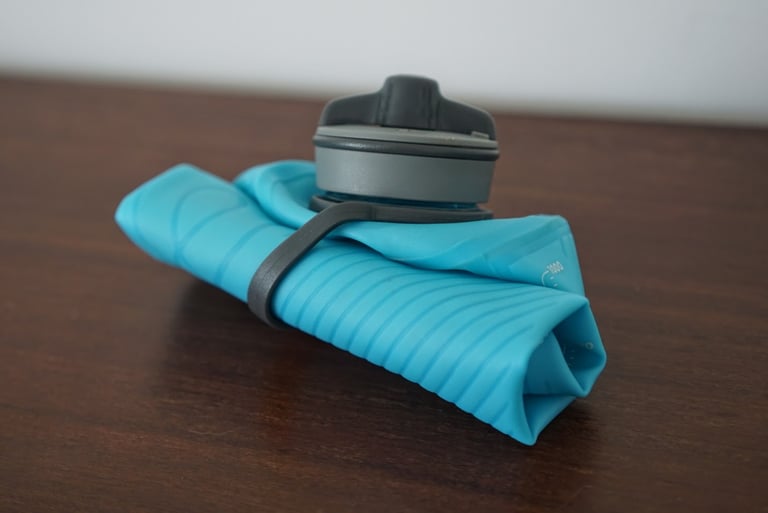 HydraPak Flux 1L bottle rolled down and secured with its toggle strap, ready to stash.