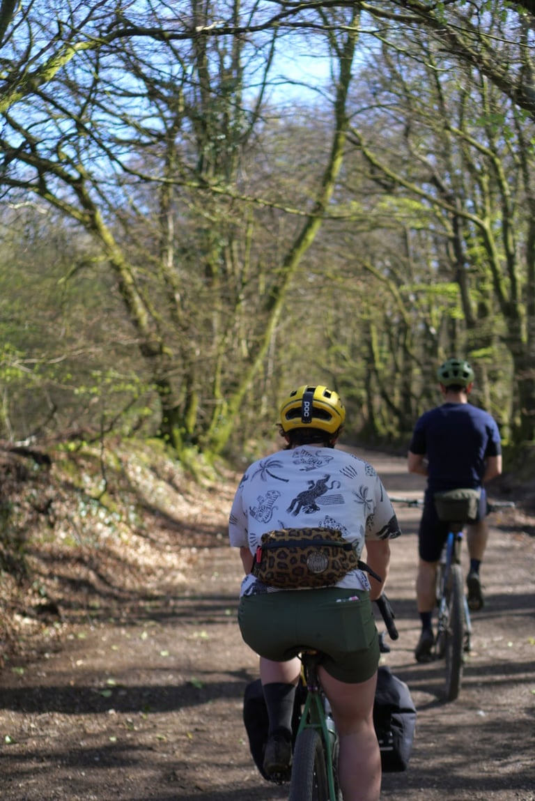Rear view of a rider in green Key Shorts with a leopard-print hip pack on a bike with panniers.