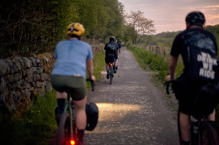 Rider on a Fairlight Faran 2 at dusk on a walled lane, its dynamo headlight lighting the road ahead of the group.