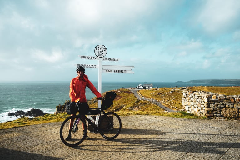 Jon with his loaded bike at the Land's End signpost, starting his UK ride for Cycling Through A Pandemic.