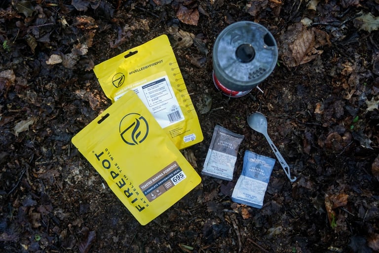 Firepot toasted banana and baked apple porridge pouches with Outdoor Provisions nut butter sachets, a spork and a stove.