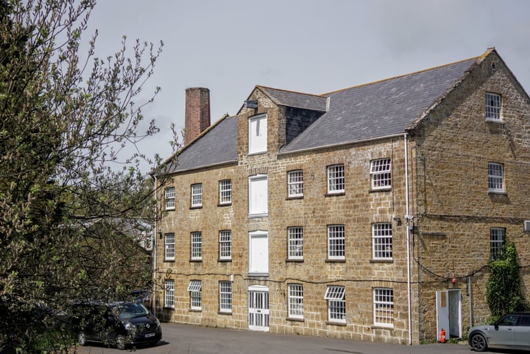 Firepot Food's Dorset stone mill in Bridport, a multi-storey building with slate roof and a brick chimney.
