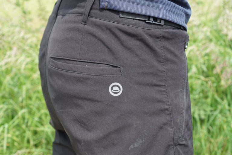 Rear of the Chapeau Gravel Short showing an open-topped back pocket, round logo and waist buckle.