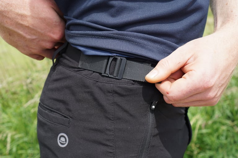 Hands adjust the waistband buckle tab on the Chapeau Gravel Short.