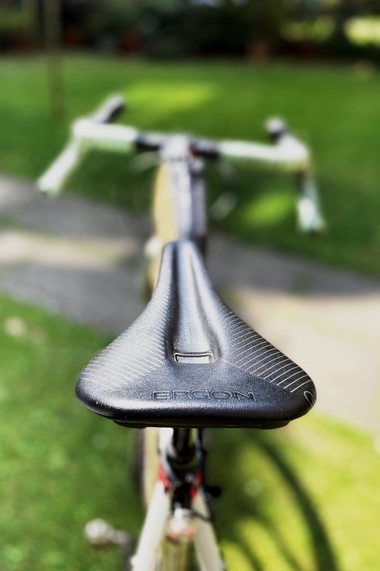 Ergon SR Pro saddle seen from behind the bike, with drop handlebars blurred in the background.