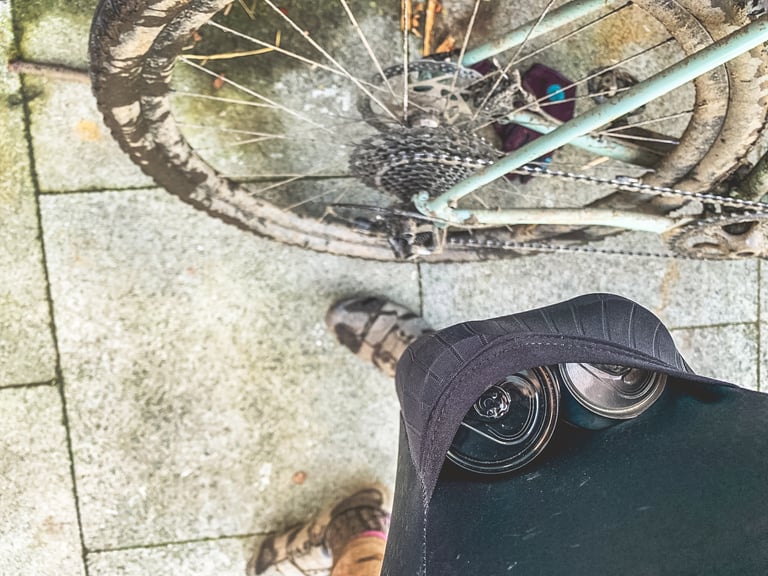Two cans of beer sit in the thigh pocket of Lusso Adventure bib shorts, seen from above the rider.