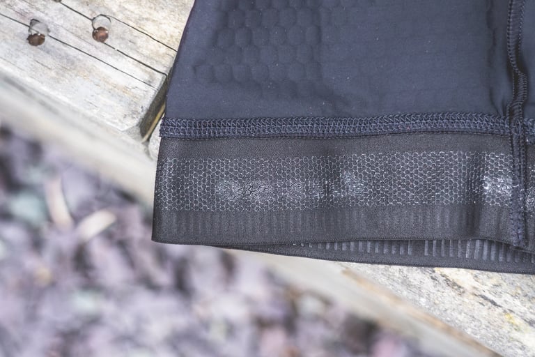 Close-up of a Lusso Adventure bib short leg hem with the wide silicone-backed gripper and flat stitching.