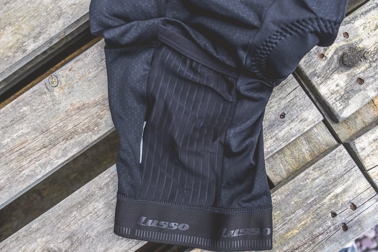 Leg pocket of the Lusso Adventure bib shorts in ribbed black fabric, with the leg hem below.