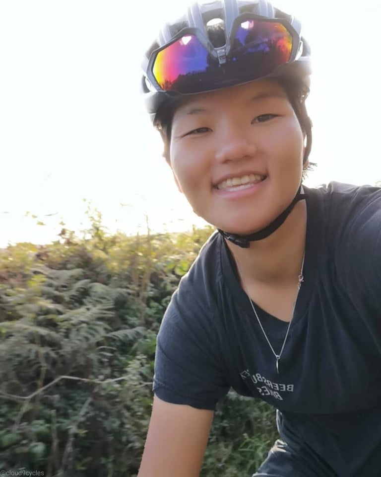 Ultra Distance Scholarship recipient Tamzin Dewar grins in a helmeted selfie, sunglasses pushed up, beside bracken.