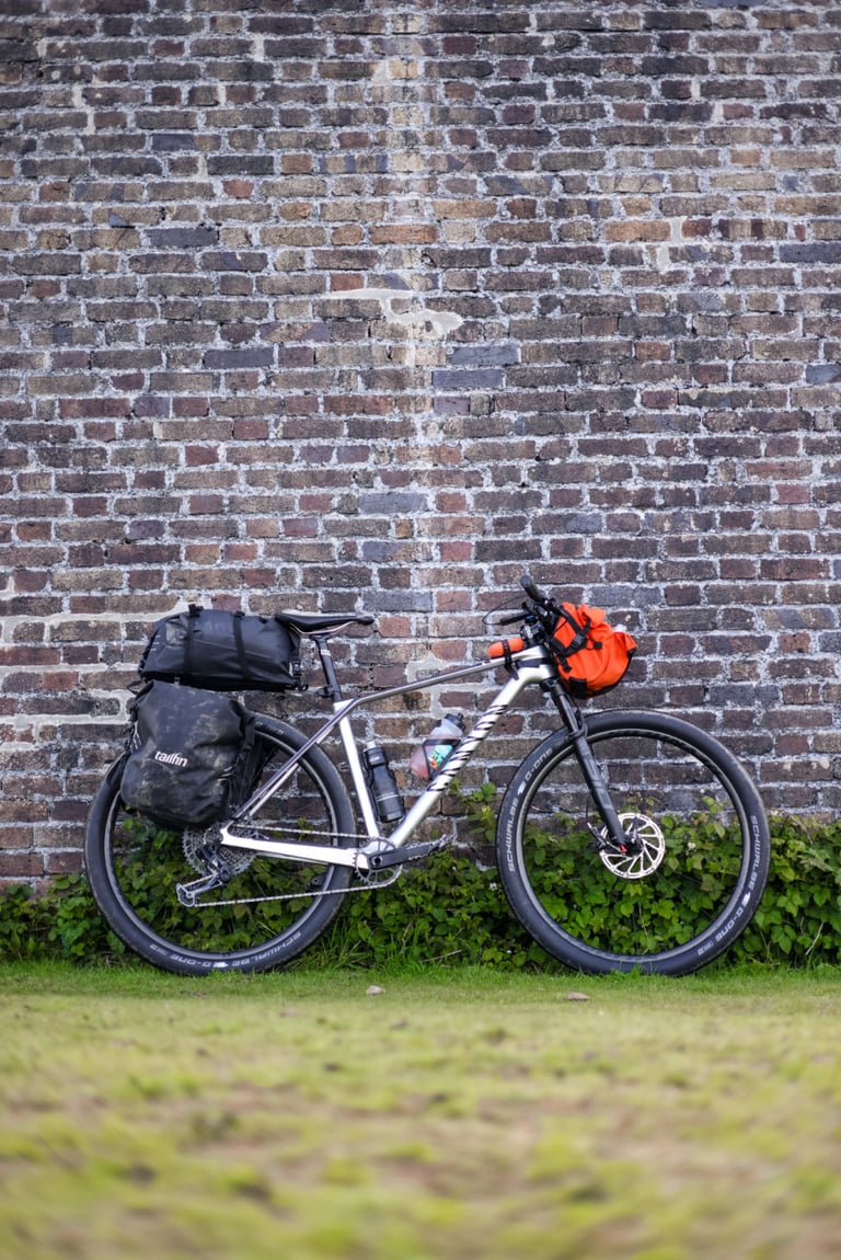 Restrap Bar Pack on a hardtail mountain bike loaded for touring, leaning against a brick wall.