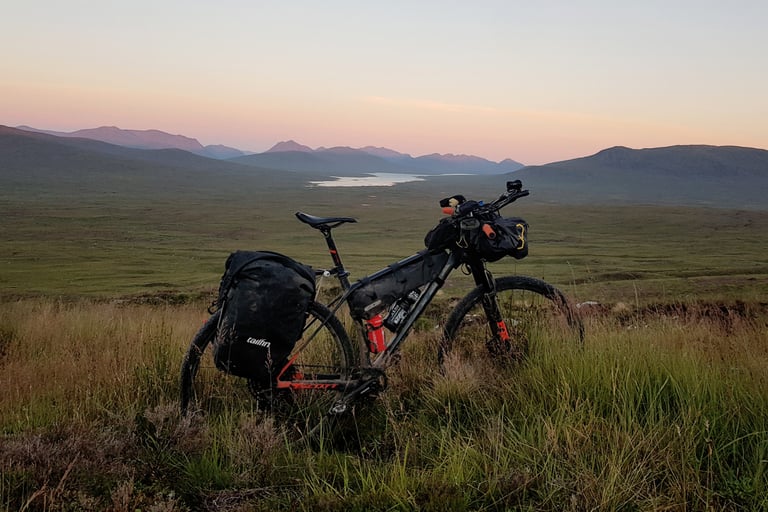 Loaded hardtail with Tailfin pannier, frame bag and bar bag, as ridden on the self-sufficient GBDURO, in moorland at dusk.
