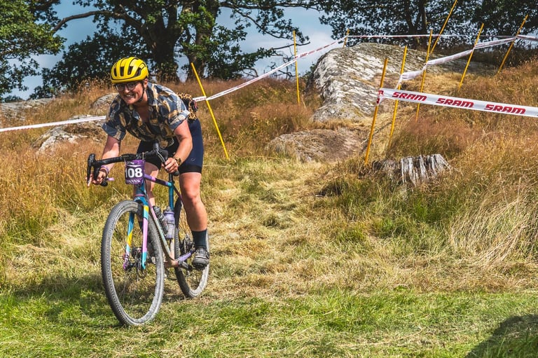 Rider on a gravel bike with WTB CZR carbon wheels descends a grassy slope between taped course markers at Grinduro Wales.
