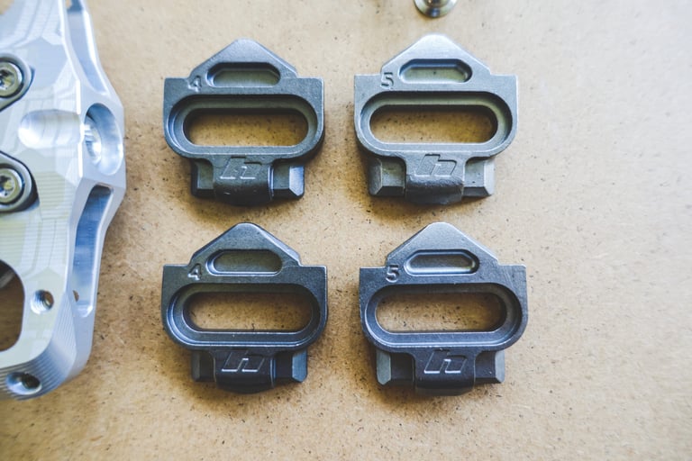 Four Hope Union cleats stamped 4 and 5 for degrees of float, laid beside a Union Trail pedal body.