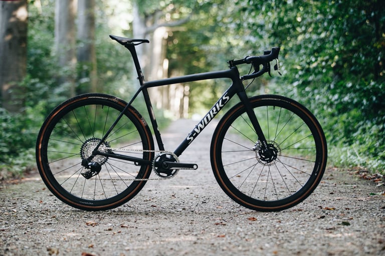 Complete 2021 Specialized S-Works Crux in black with tan-wall tyres, on a gravel track in woodland.