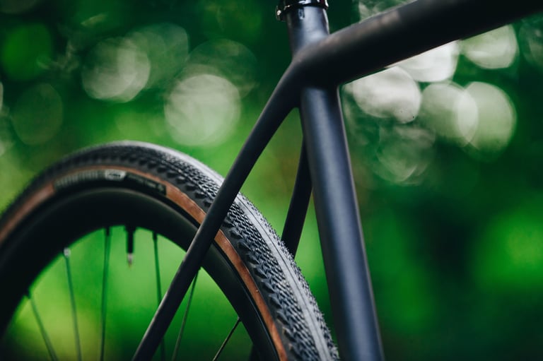 Close-up of a 2021 Specialized Crux seat tube and rear tyre with tan sidewall against a blurred green background.