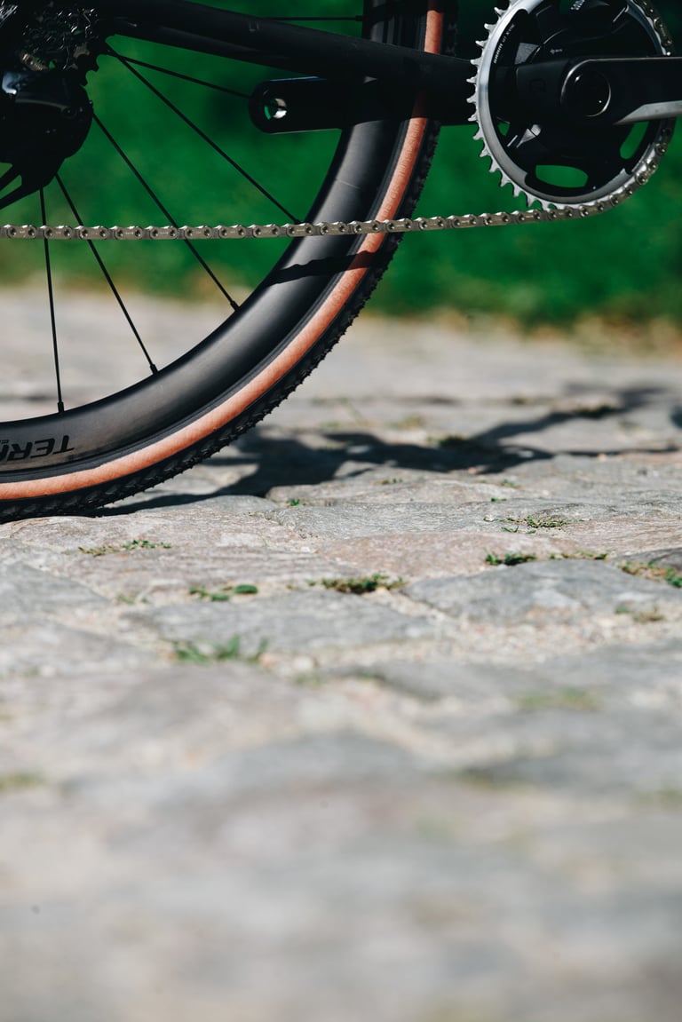 Specialized Crux 1x chainring, chain and Roval Terra wheel with tan sidewall tyre, parked on cobbles.