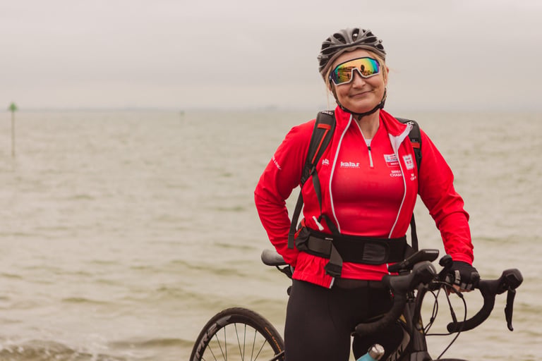 Emma Hopgood, a Breeze ride leader in a red jacket, stands with her road bike by the sea after the Women's Tour of Britain.