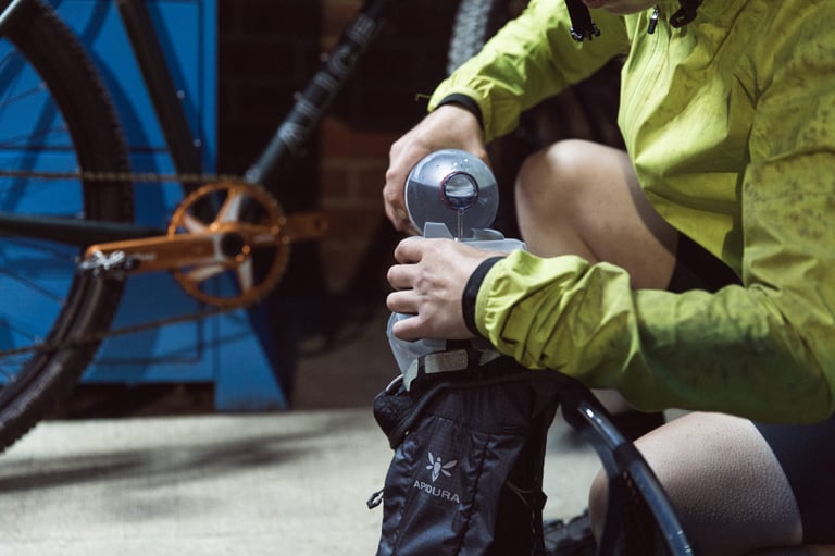 Roll-top bladder of the Apidura Racing Hydration Vest being refilled from a flask without removing it from the pack.