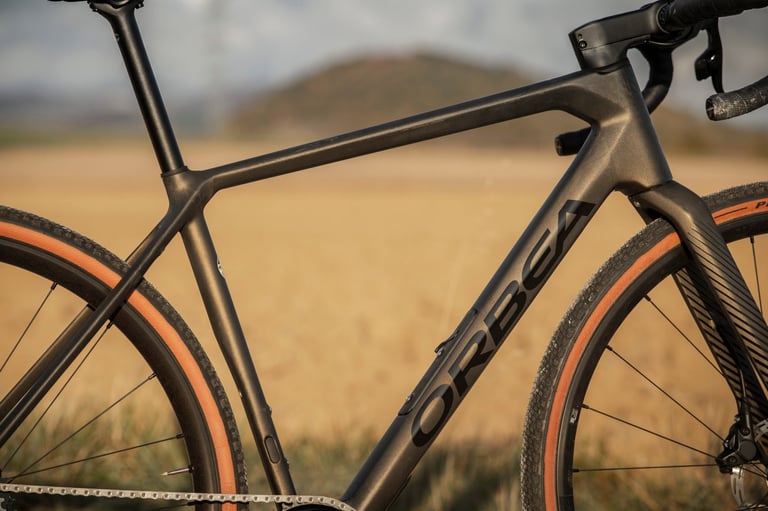 Close-up of the 2022 Orbea Terra carbon frame in dark bronze, with the Orbea logo on the downtube and tan-wall tyres.