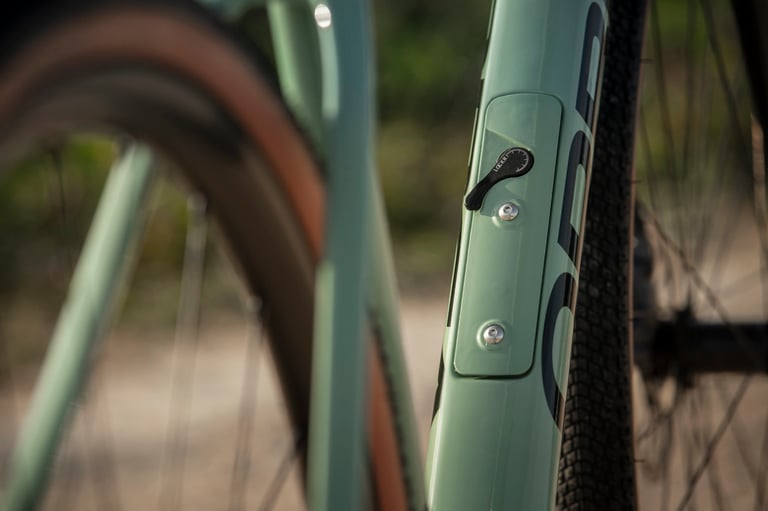 Orbea Terra Lockr storage lid with its latch and bottle cage bolts on the downtube of a green frame.