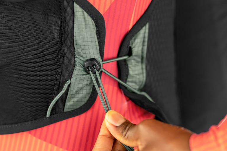 Hand pulls the bungee cord toggle that adjusts the fit of the Apidura Racing Hydration Vest.