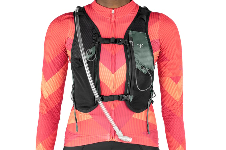 Front view of the Apidura Racing Hydration Vest worn over a red jersey, with chest straps, mesh pockets and hose.